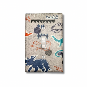 Handmade Roaring Wild Dinosaur Explorer decorative light switch cover featuring hand-drawn T-rex, triceratops, and tribal patterns on natural linen background—kids room switch plates from Black-owned home décor.