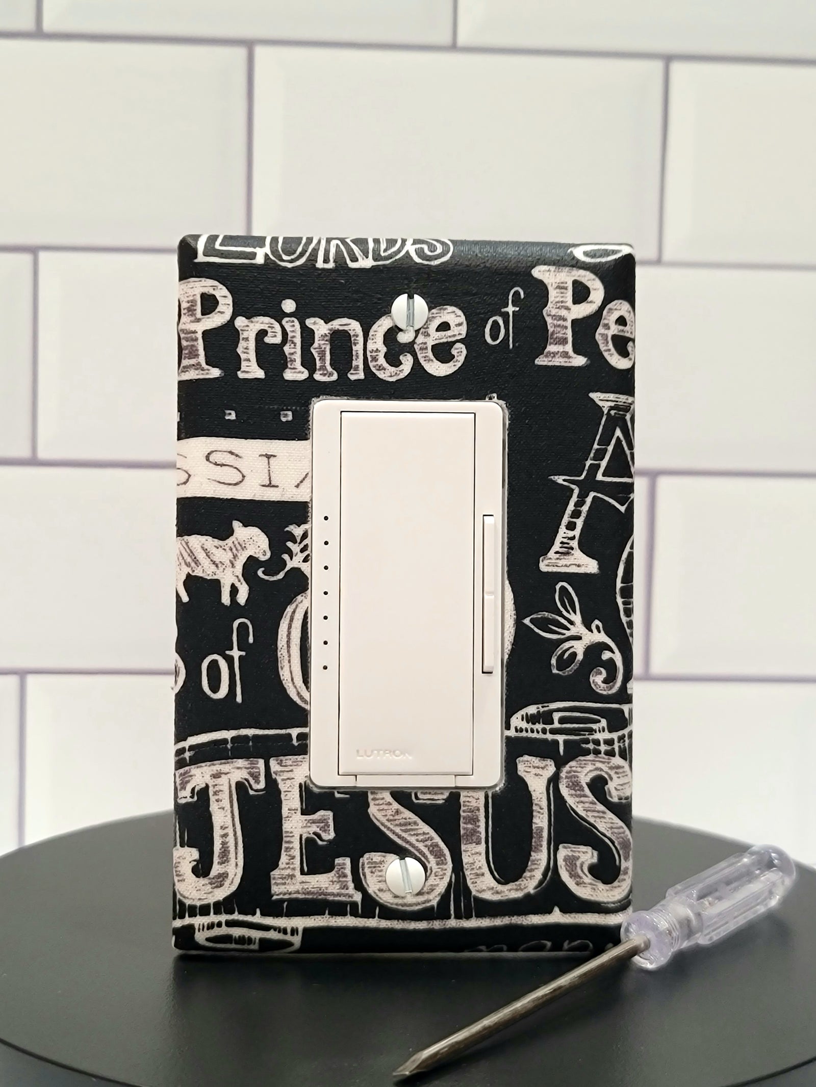 Handmade Sacred Declaration decorative light switch cover featuring Christian typography with Prince of Peace, Jesus, Lamb of God on black background—faith-based switch plates from Black-owned home décor.