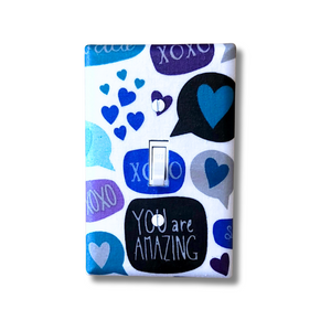Decorative light switch cover with blue and purple hearts, speech bubbles, and 'You are Amazing' text on a white background.