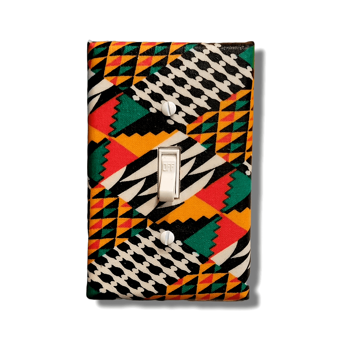 Handmade light switch cover with kente-inspired geometric patterns in forest green, red-orange, golden yellow, black, and cream featuring traditional African stepped triangles, diagonal stripes, and zigzag designs for cultural heritage home décor
