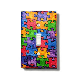 Handmade Every Piece Fits Together decorative light switch cover featuring colorful interlocking puzzle pieces in rainbow spectrum—autism awareness and inclusion switch plates from Black-owned home décor.