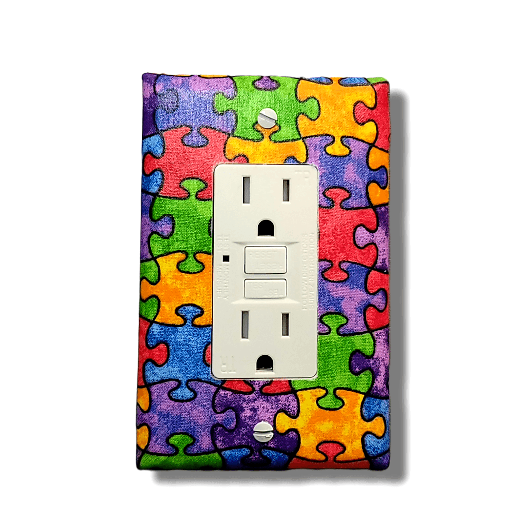 Handmade Every Piece Fits Together decorative light switch cover featuring colorful interlocking puzzle pieces in rainbow spectrum—autism awareness and inclusion switch plates from Black-owned home décor.